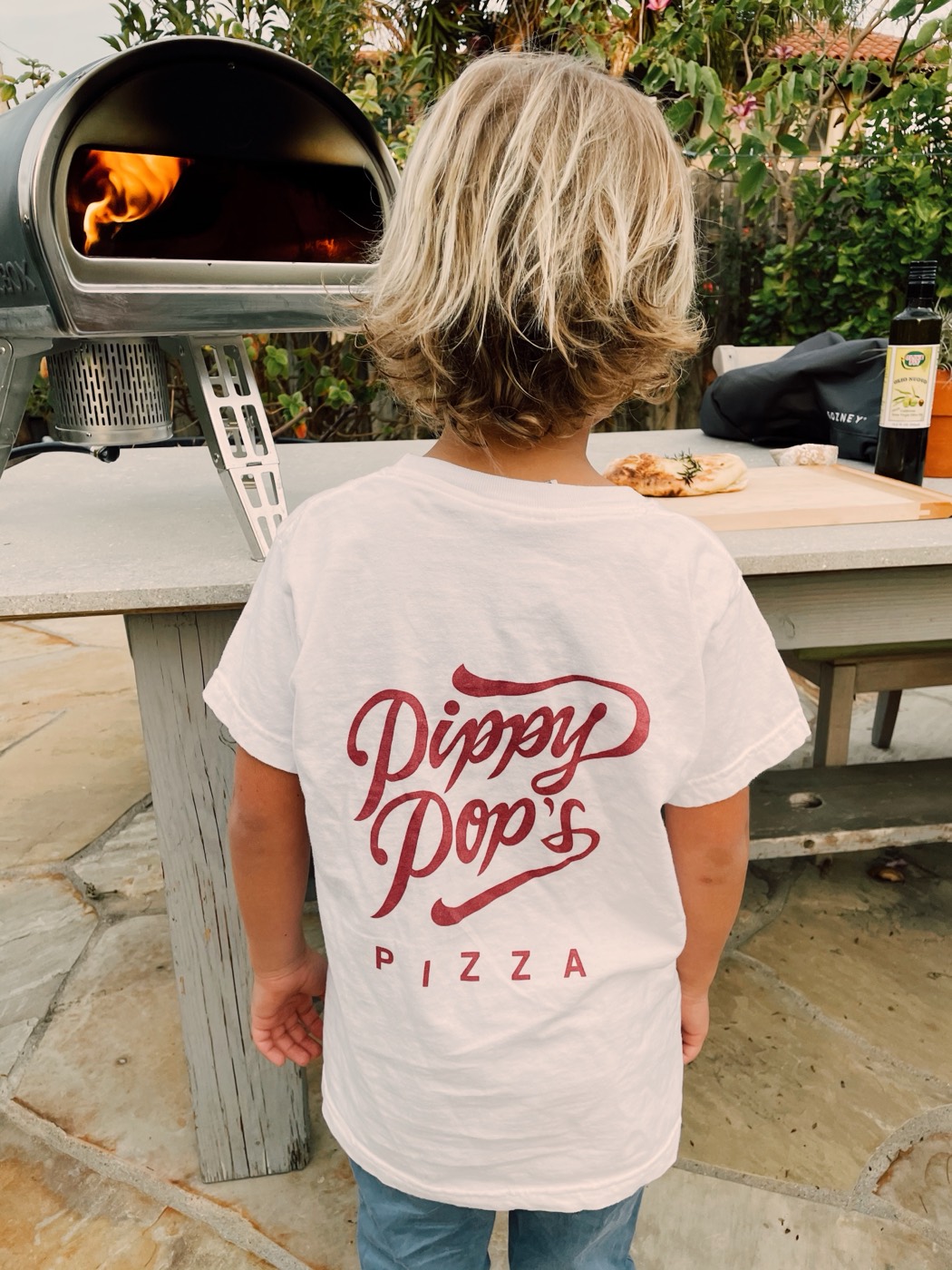 Kid at the wood-fired oven in the backyard